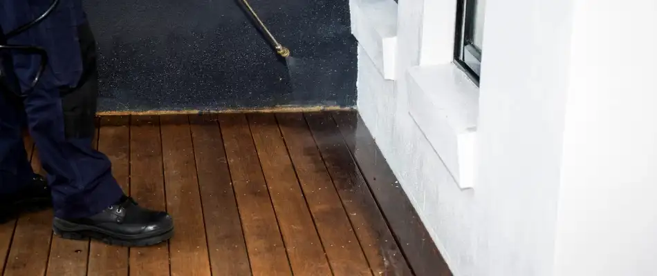 Professional applying perimeter pest control treatment to home